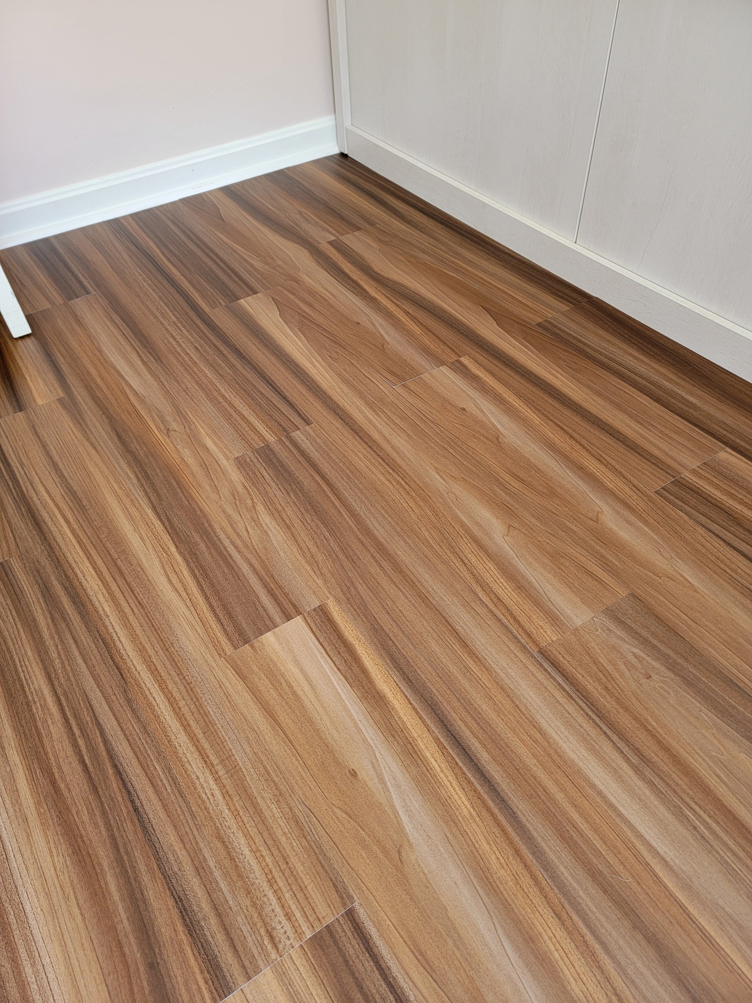 Reddish brown peel and stick vinyl flooring installed in a room viewed at an angle