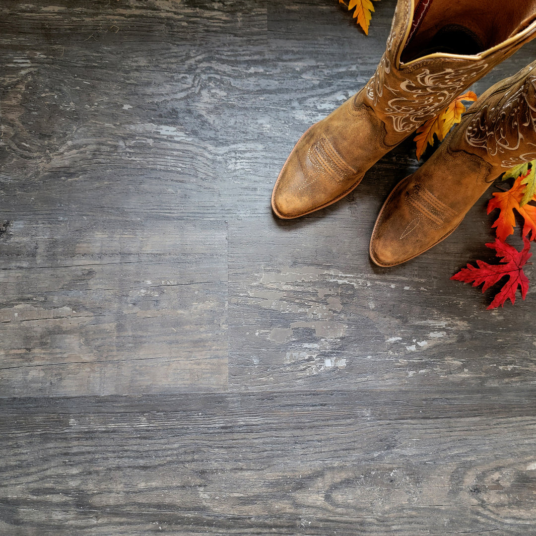 Rustic vinyl flooring planks with cowboy boots and fall leaves