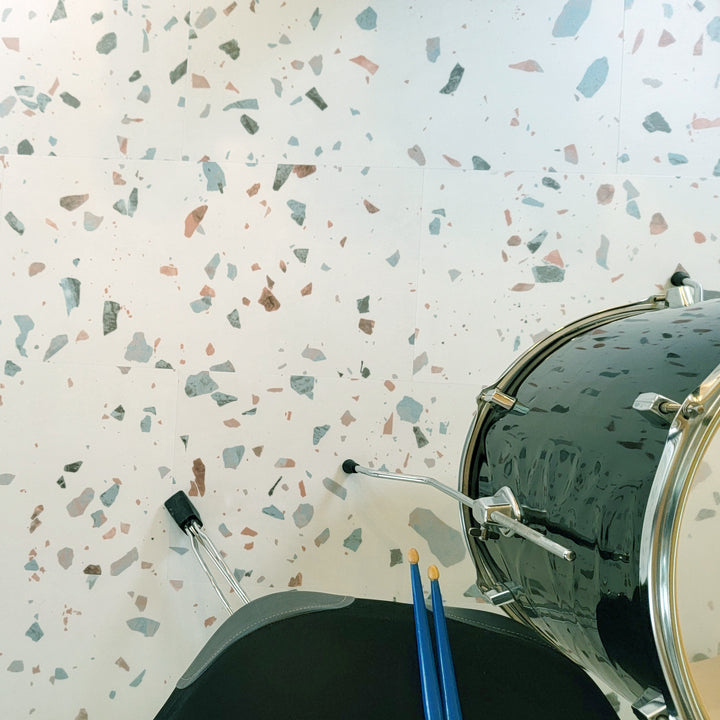 Earl Grey terrazzo vinyl tiles with black floor drum, drum throne and blue drumsticks