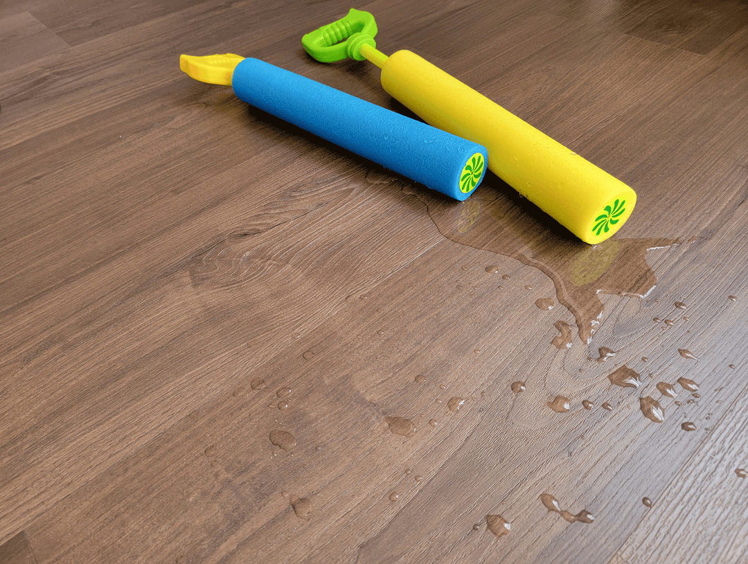 Dark brown vinyl flooring with pool toys and water on the floor