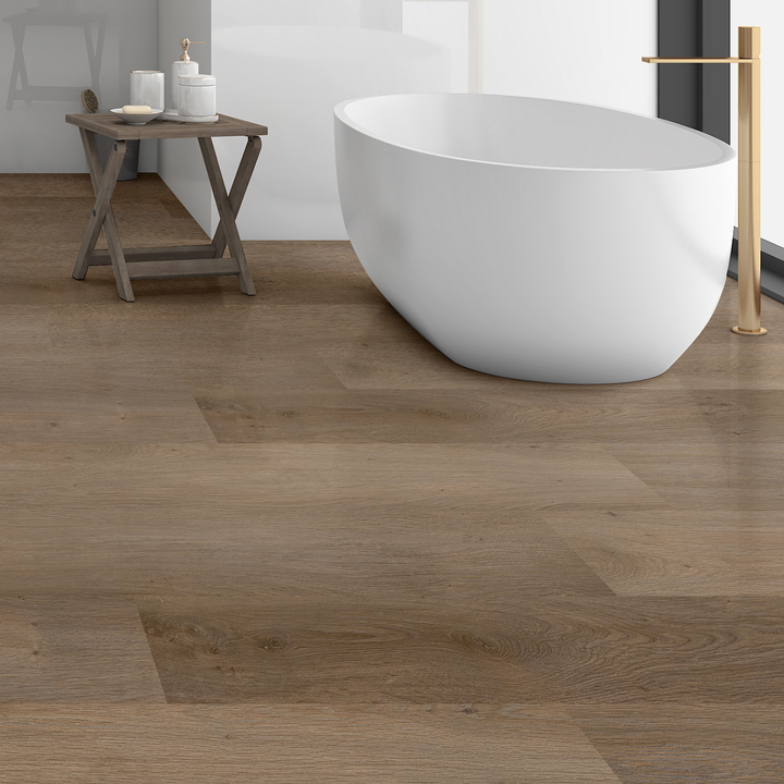 Allure Vanilla Latte Oak plank flooring in a bathroom with a deep soak tub and gold tub filler. A side table is beside the tub with toiletries on top