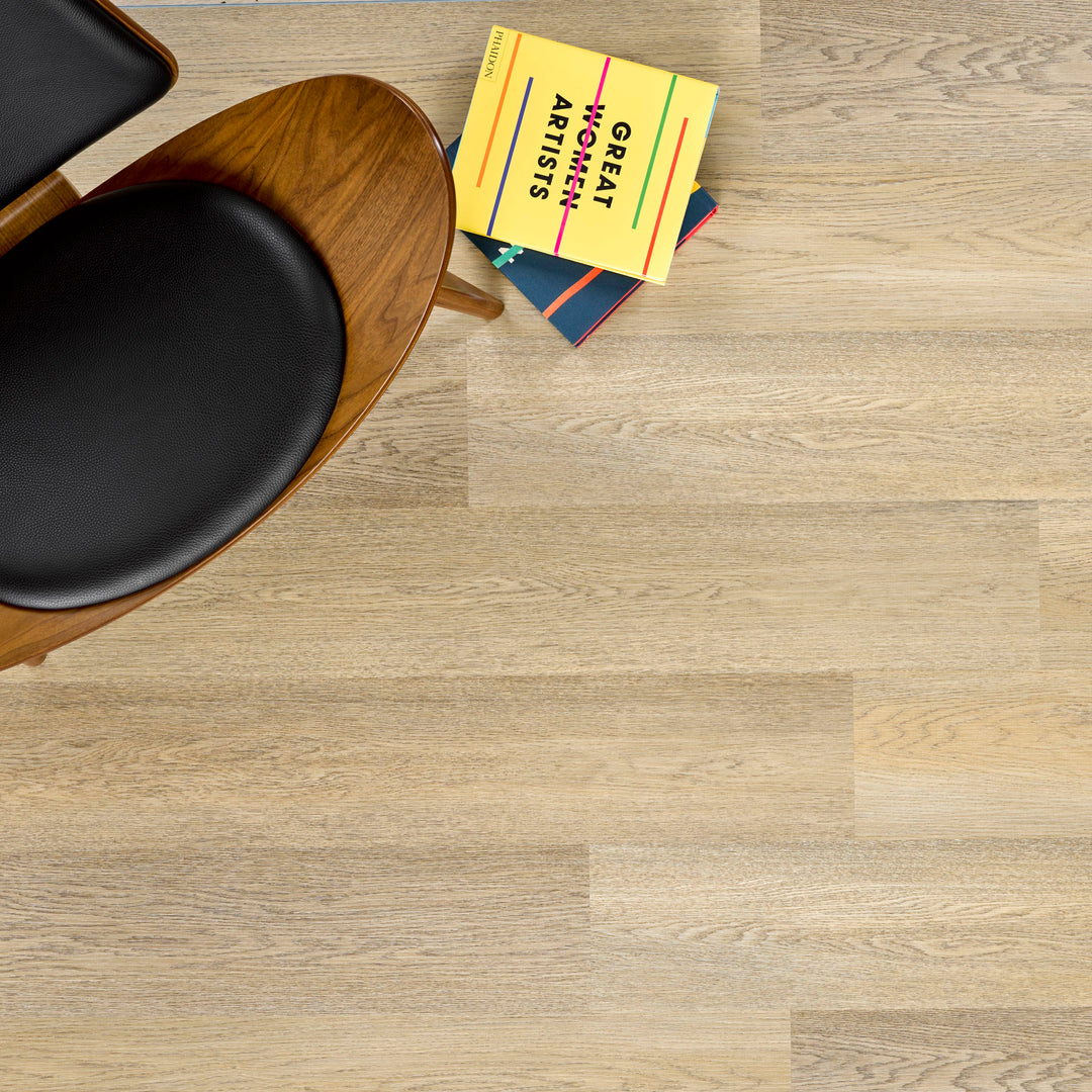 Allure SRP TPU Flooring in Pure Oak Sunrise installed floor view from above with a black and wood chair and books