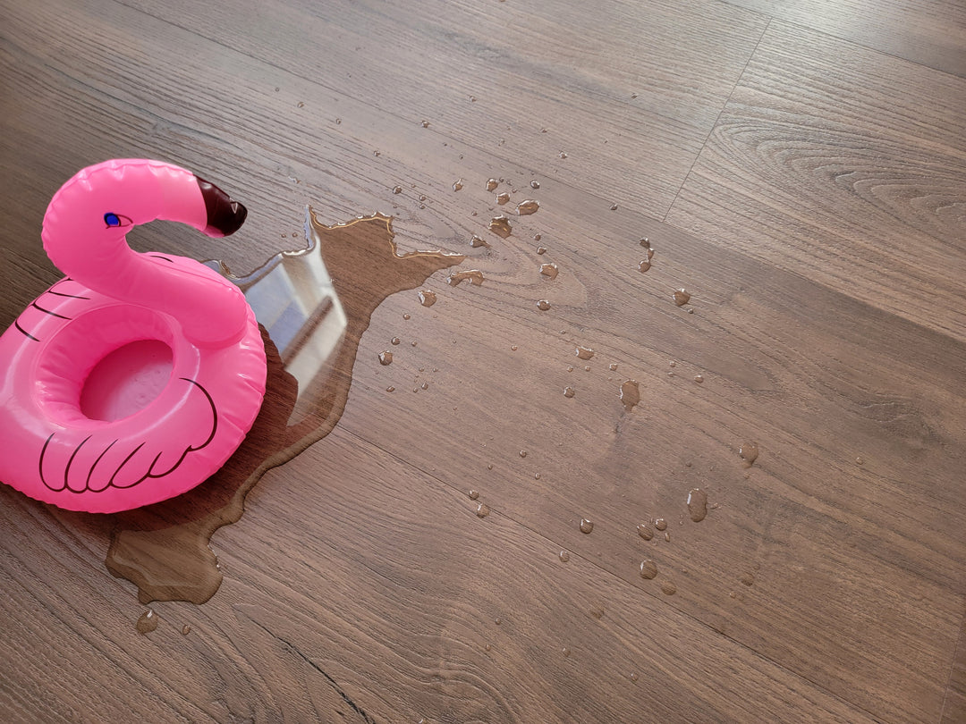 Dark brown vinyl plank flooring with Flamingo Inflatable and a puddle of water